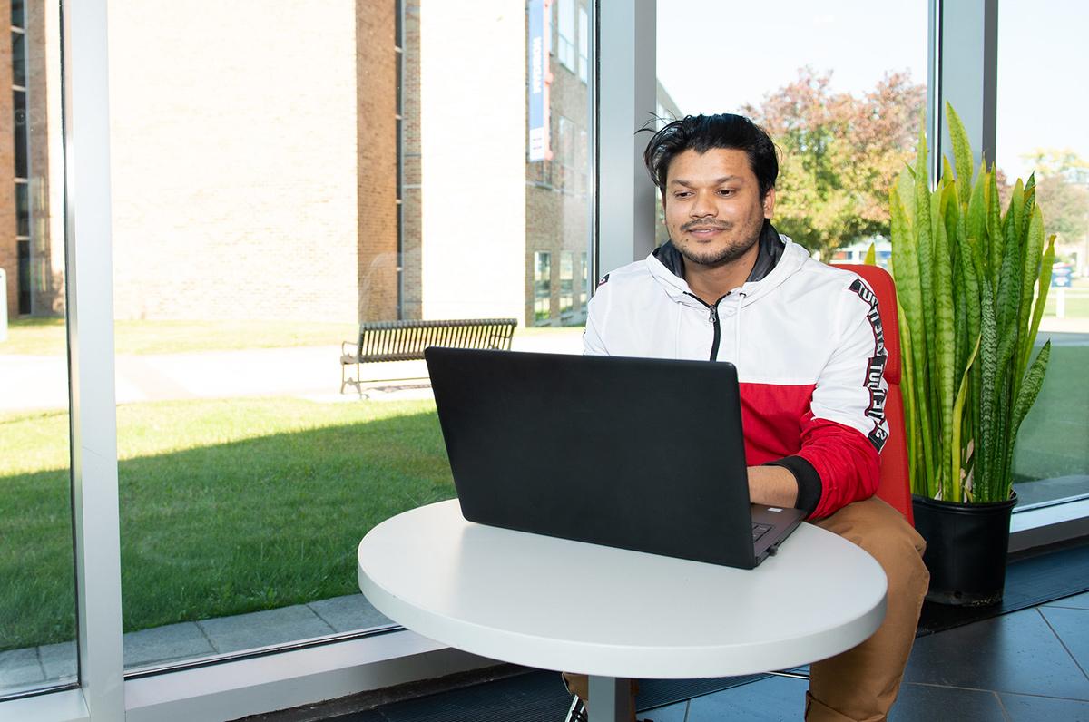 young male hispanic student using a laptop in Taft Hall